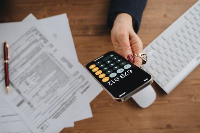 Photo d'illustration : une calculatrice et des documents posés sur un bureau
